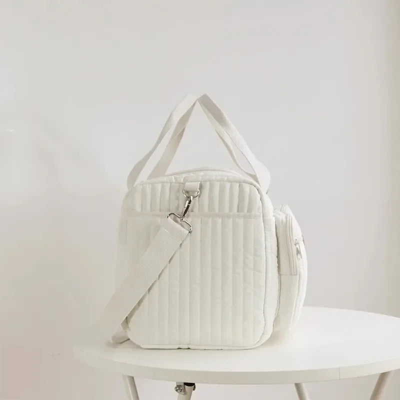 Vue latérale du sac à langer matelassé écru avec bandoulière