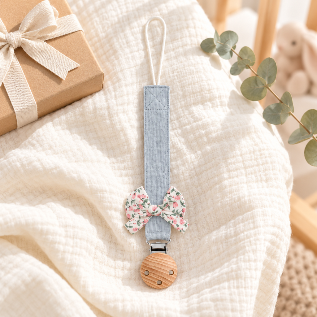Attache-tétine en tissu bleu brume avec nœud fleuri et pince en bois