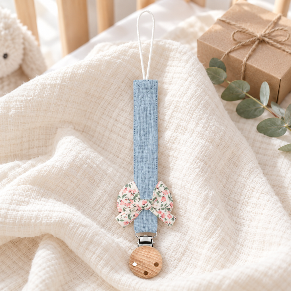 Attache-tétine en tissu bleu pastel avec nœud fleuri et pince en bois