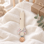 Attache-tétine en tissu écru avec nœud fleuri et pince en bois