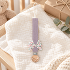Attache-tétine en tissu mauve avec nœud fleuri et pince en bois