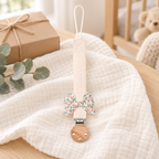 Attache-tétine en tissu rose pastel avec nœud fleuri et pince en bois