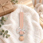 Attache-tétine en tissu rose pêche avec nœud fleuri et pince en bois