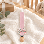 Attache-tétine en tissu rose tendre avec nœud fleuri et pince en bois