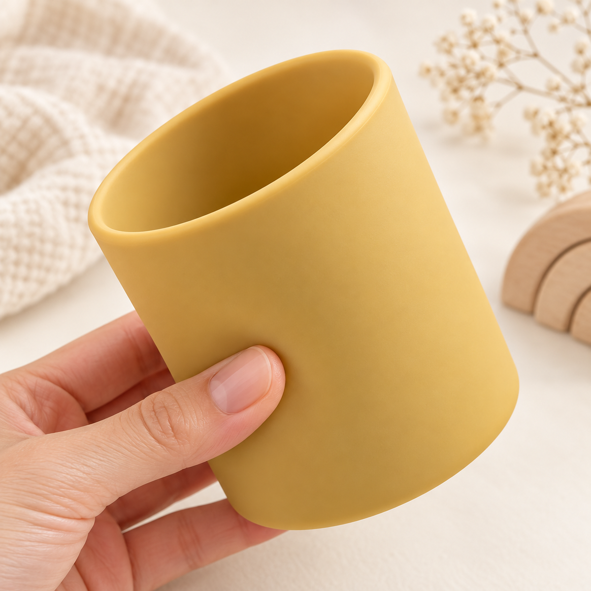 Détail de la souplesse du gobelet bébé en silicone moutarde