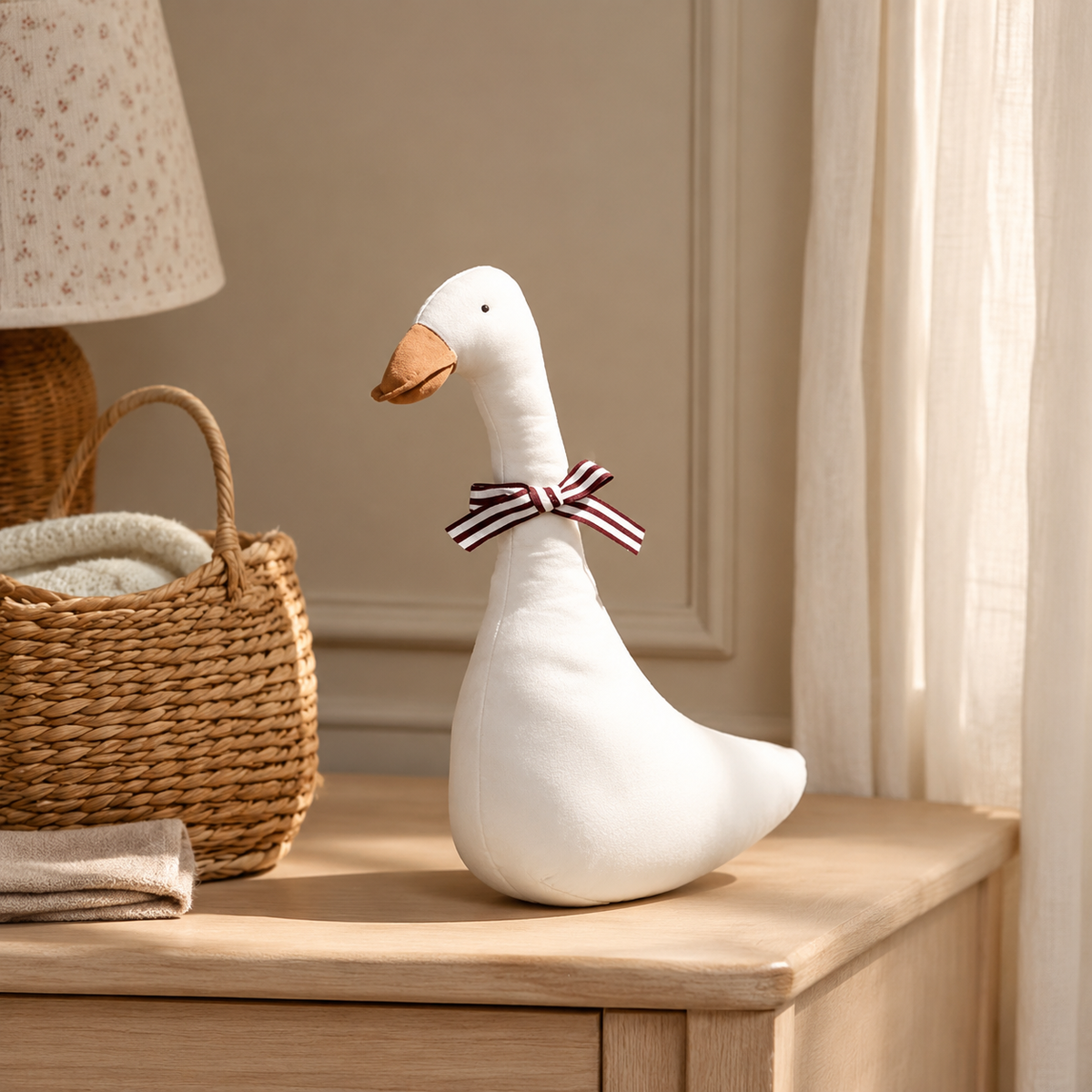 Oie décorative en tissu blanc avec nœud rayé sur une commode de chambre bébé