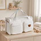 Sac à langer matelassé écru avec écusson ours dans une chambre de bébé