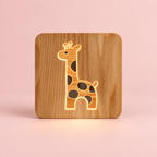 Veilleuse bébé girafe en bois LED allumée sur fond rose poudré