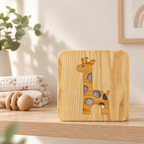 Veilleuse girafe en bois éteinte sur une étagère de chambre bébé